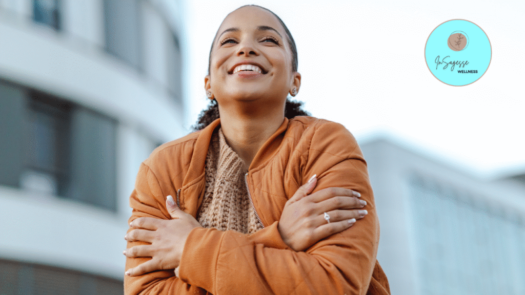 Smiling woman embracing herself outdoors, supported by a Wellness Coach.