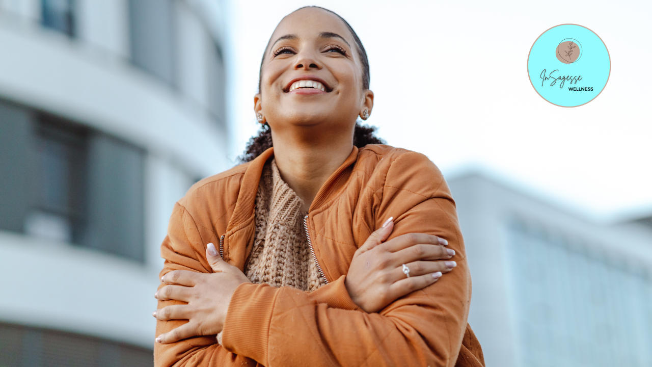 Smiling woman embracing herself outdoors, supported by a Wellness Coach.