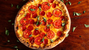 Pepperoni pizza with fresh basil on a wooden tabletop.